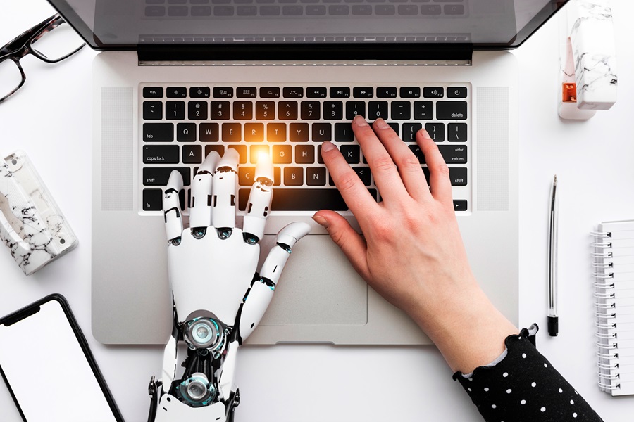 mano umana e mano robot che digitano su un pc